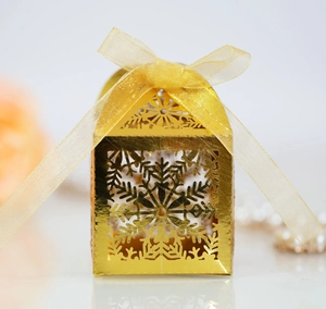 Close-up of golden laser-cut snowflake gift box with metallic finish and ribbon bow