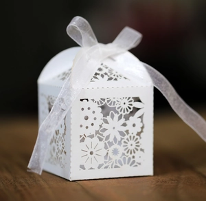 Détail de découpe laser florale sur boîte de mariage blanche avec ruban satiné