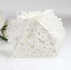 Detail of white laser-cut wedding favor box with intricate heart and butterfly patterns