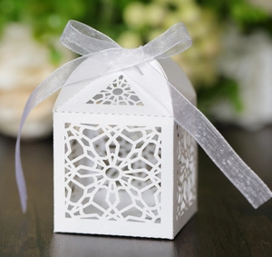 Elegant white laser-cut wedding favor box with intricate hollow design and silver ribbon
