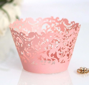 Detailed laser-cut pink paper cupcake wrapper featuring intricate floral lace patterns