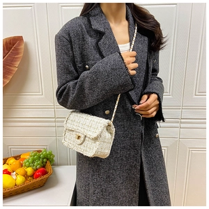 Detailed shot of cream tweed plaid crossbody bag with gold chain strap on grey wool coat