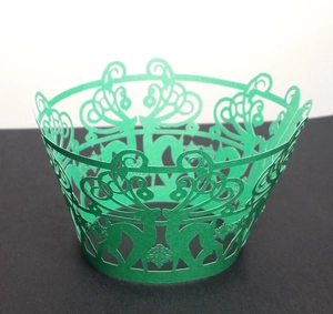 Detail view of green laser-cut cupcake wrappers with Christmas reindeer and snowflake motifs
