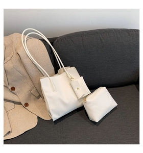 Minimalist white litchi pattern tote bag with matching pouch on a grey sofa