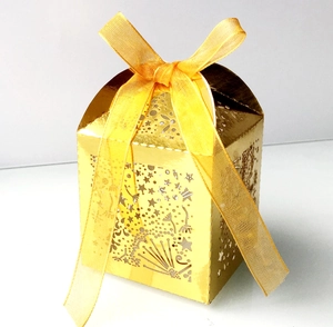 Macro detail of laser-cut gold wedding favor box with star patterns and yellow ribbon