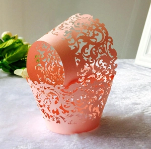 Close-up of laser-cut peach vine pattern lace cupcake liners for wedding decor