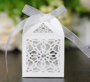 Detail of white laser-cut wedding favor box with star patterns and silver ribbon bow