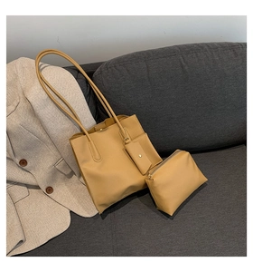 Detailed view of the large camel leather tote set on a grey sofa with a blazer