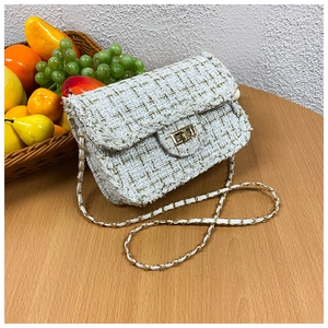 Detailed close-up of tweed chain bag featuring golden metallic twist lock and woven texture
