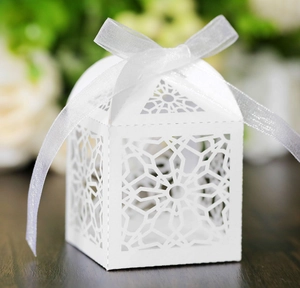 Macro detail of white laser-cut wedding favor box with star patterns and organza ribbon