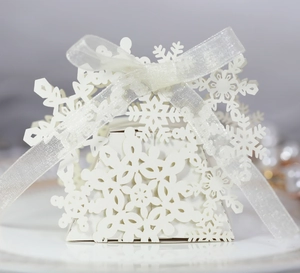 Close-up of laser-cut white snowflake hollow candy box with elegant silk ribbon bow