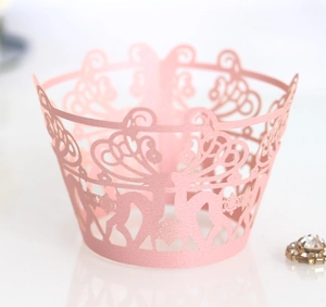 Macro detail of pink laser-cut cupcake wrapper with reindeer and snowflake lace pattern