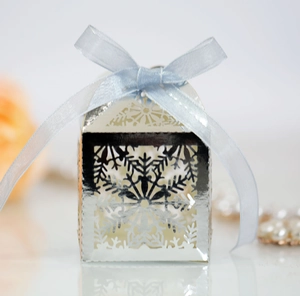 Close-up of laser-cut snowflake candy box in mirror silver with light blue ribbon bow