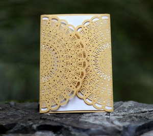 Macro shot of laser-cut mandala pattern on golden wedding invitation cards