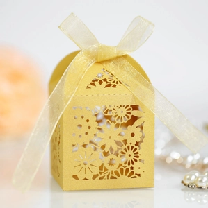 Gros plan des motifs floraux découpés au laser sur une boîte à bonbons dorée de mariage
