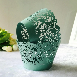 Detailed close-up of dark green laser-cut paper cupcake wrappers with vine patterns