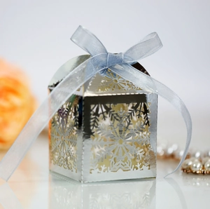 Close-up of laser-cut snowflake candy box with elegant light blue ribbon bow