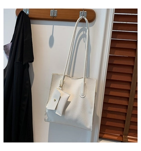 Close-up of white pebble grain tote bag with mini envelope pouch on a wooden hanger