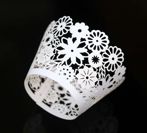 Detailed close-up of laser-cut white daisy lace cupcake wrappers for wedding decor