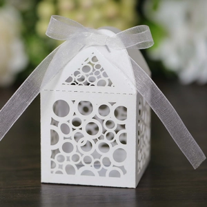 Detailed view of white laser-cut house-shaped favor box with round patterns and ribbon