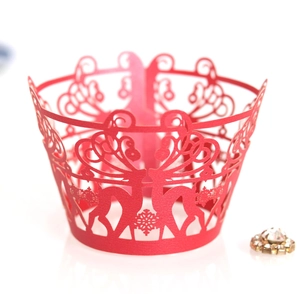 Macro shot of laser-cut red cupcake wrapper with reindeer and snowflake lace motifs