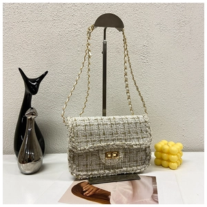 Detail of tweed crossbody bag with golden chain strap and woven plaid texture