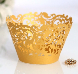 Macro shot of gold laser-cut hollow filigree cupcake wrappers for elegant party desserts