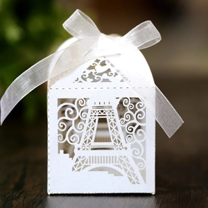 Laser cut white Eiffel Tower favor box with heart patterns and a white silk bow decoration
