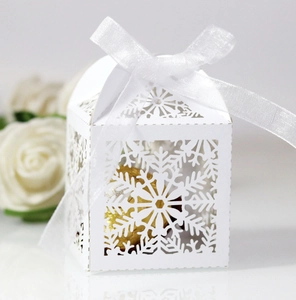 Detail of laser-cut snowflake gift box with white ribbon and chocolate inside