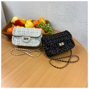 Close-up of black and white tweed crossbody bags with gold chain straps and metal locks