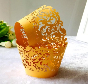 Macro detail of laser-cut lace pattern on reflective gold cupcake wrappers for events