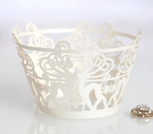 Detail of laser-cut cupcake wrapper featuring delicate white deer and snowflake patterns