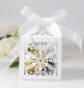 Detailed laser-cut snowflake gift box with white organza ribbon and golden chocolates