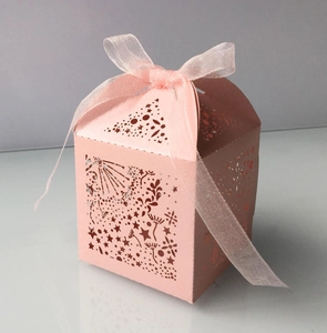 Detail of pink laser-cut star paper favor box with a matching organza ribbon bow