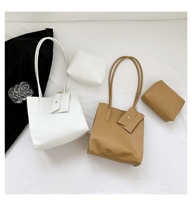 Flat lay of minimalist leather tote bag sets in white and brown with matching pouches