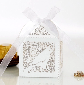 Macro detail of white laser-cut love bird candy box with delicate ribbon bow and floral pattern