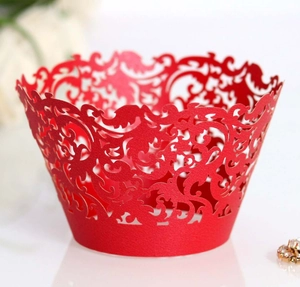 Detail of red laser-cut cupcake wrapper with intricate floral scroll patterns