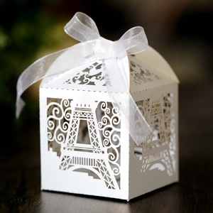 Elegant white laser-cut Eiffel Tower gift box with white ribbon bow on wooden surface