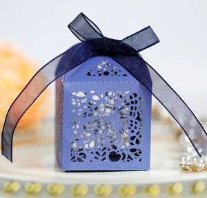 Detailed close-up of purple laser-cut wedding favor box with ribbon and floral patterns