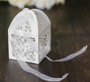 Macro view of white laser-cut hollow candy box with pearl paper and white organza ribbon