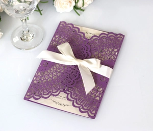 Close-up of laser-cut purple lace wedding invitation with a white satin ribbon bow