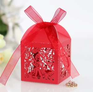 Close-up of red laser-cut candy box with hollow butterfly patterns and silk ribbon bow