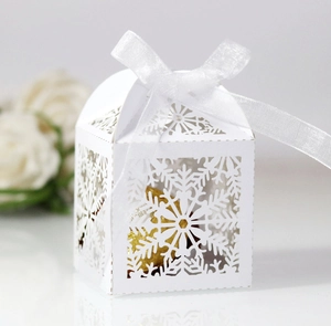 Macro detail of white snowflake laser-cut gift box with silk ribbon and gold candy
