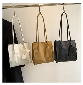 Detailed view of three minimalist leather tote bags in white, khaki, and black with mini pouches