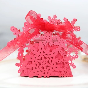 Close-up of red Christmas snowflake laser-cut candy gift box with a red organza ribbon bow
