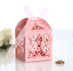 Close-up of pink laser-cut candy box with geometric star patterns and satin ribbon bow