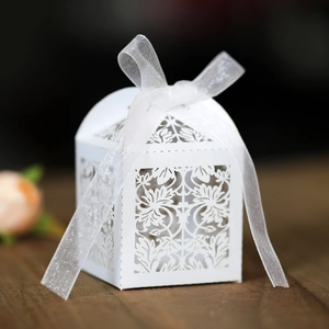 Detailed laser-cut white wedding favor box with floral patterns and a white ribbon bow
