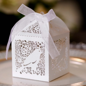Detail of laser-cut white favor box with intricate bird patterns and organza ribbon bow