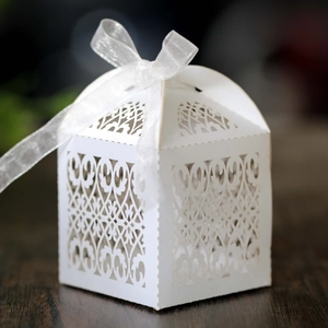 Detailed laser-cut scrollwork on white wedding favor box with a silk ribbon bow