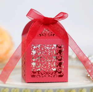 Détail d'une boîte cadeau rouge ajourée avec motifs floraux au laser et ruban en organza
